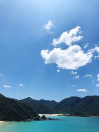 Scenic view of sea and mountains against blue sky