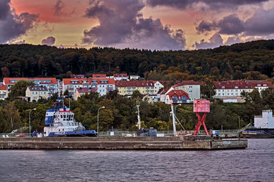 Scenic view of lake by buildings against sky at sunset