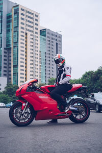 Man riding motorcycle on road against buildings