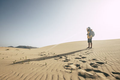 Man standing on sand dune in desert against sky