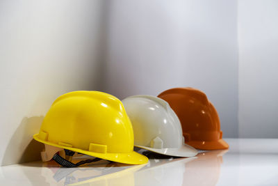 Close-up of yellow hat on table against wall