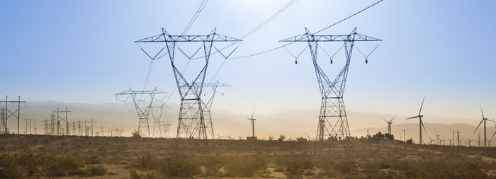 Electricity pylon on field against sky