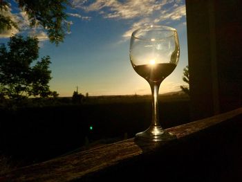 Close-up of wineglass on table against sky during sunset