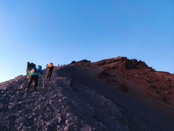 Rear view of hikers on mountain against clear sky