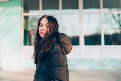 Portrait of young smiling brunette woman in winter jacket looking at camera. person