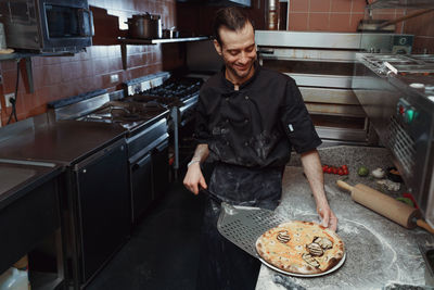 Chef preparing italian pizza in restaurant kitchen 