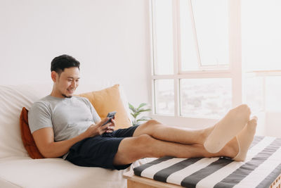 Young woman using laptop while sitting on bed at home