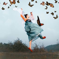 Low angle view of woman jumping against sky