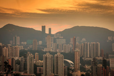 Modern buildings in city against sky during sunset