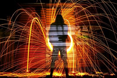 Rear view of person spinning wire wool at night