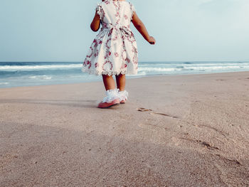 Rear view of woman standing at beach