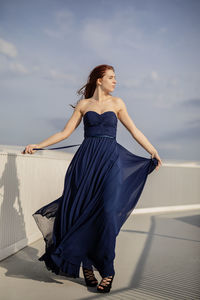 Young woman wearing blue dress while standing on building terrace