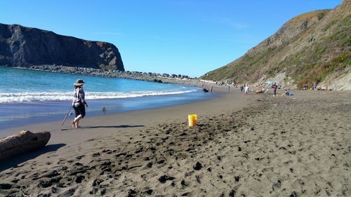 Woman walking on sand against sea at beach