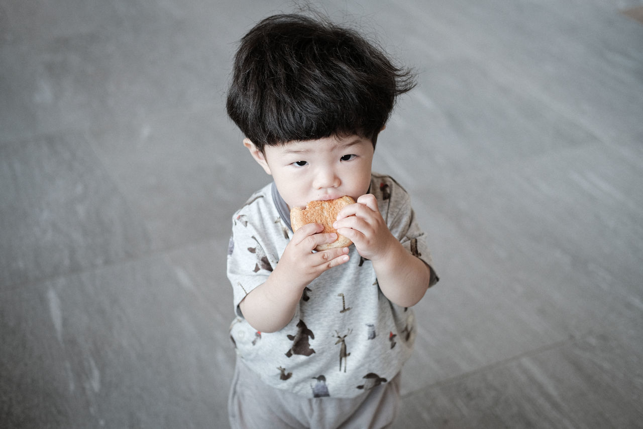 childhood, child, one person, eating, person, food, men, white, food and drink, portrait, baby, toddler, holding, casual clothing, frozen food, innocence, front view, black hair, sweet food, ice cream, indoors, sweet, human face, dairy, clothing, looking at camera, cute, skin, high angle view, portrait photography, cone, unhealthy eating, ice cream cone, frozen