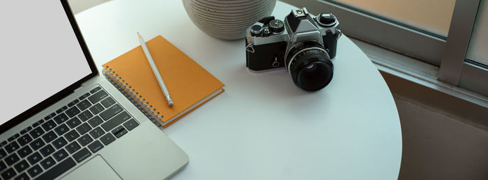 High angle view of camera with laptop on table