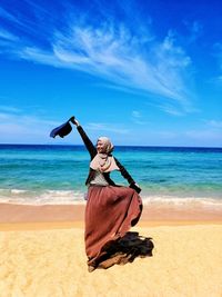 Woman with umbrella on beach against sky