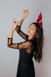 Young woman looking away while standing against white background