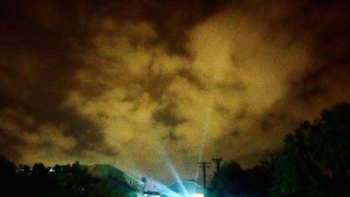 Silhouette trees against dramatic sky at night