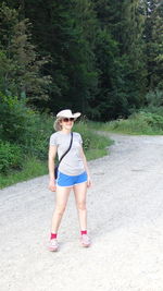 Portrait of woman standing on dirt road in forest