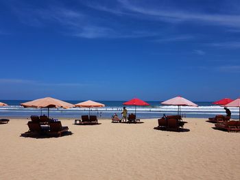 Deck chairs on beach against blue sky