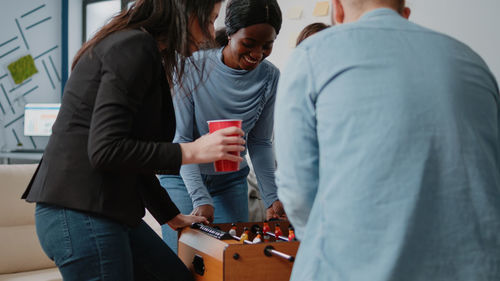 Cheerful colleagues playing foosball at office