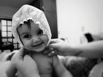 Cropped hand of mother holding smiling baby at home