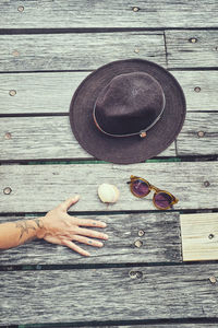 Hat, sunglasses, shell and mans hand on jetty