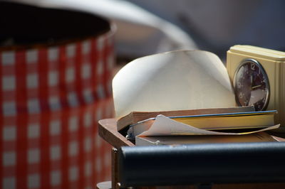 Close-up of books by clock on table at home