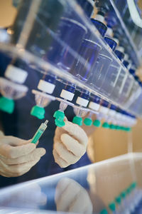 Unrecognizable cosmetologist in gloves filling syringe with chemical liquid for skin care procedure in modern beauty clinic