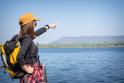 Rear view of person standing by sea against clear sky