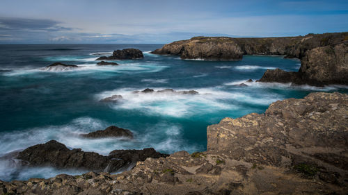 Scenic view of rocks on beach against sky
