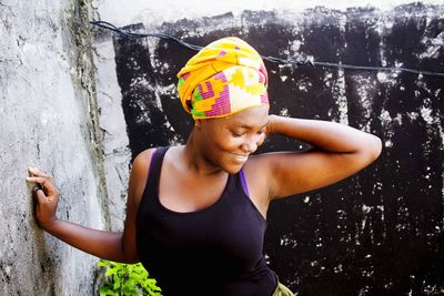 Smiling young woman standing against wall