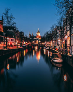 Bridge over canal amidst buildings in city at night