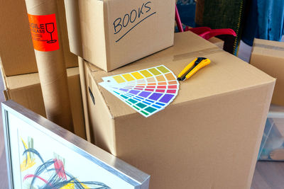 High angle view of color swatch with utility knife on cardboard box in new home