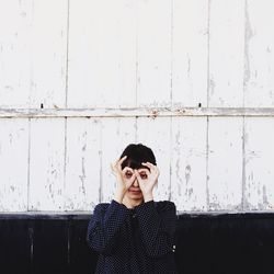 Portrait of young woman standing against wall