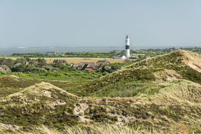 Lighthouse amidst buildings against clear sky