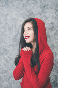 Thoughtful woman looking away while standing against wall