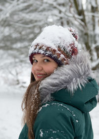 Portrait of smiling young woman standing on snow