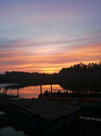 Silhouette trees by lake against sky during sunset