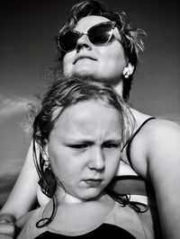 Woman wearing sunglasses with daughter against sky