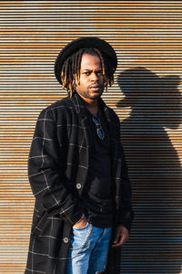 Portrait of young man standing against wall