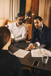 High angle view of mid adult lawyer discussing over documents with colleagues in meeting at office