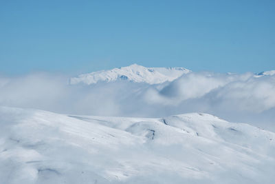 Snow covered mountain slope with clouds and bright blue sky. winter mountain landscape