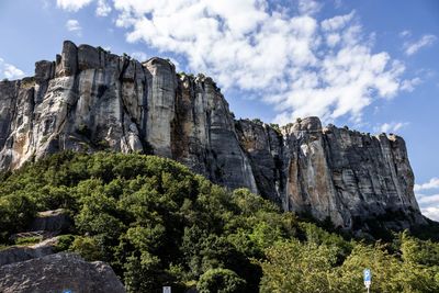 Low angle view of rocks and trees against sky