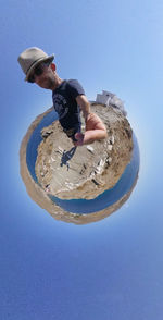 Low angle view of young man against clear blue sky