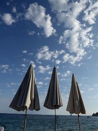 Deck chairs on beach against sky