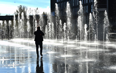 Rear view of silhouette man standing by fountain