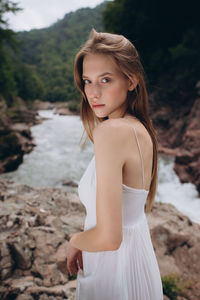Portrait of beautiful young woman standing by river