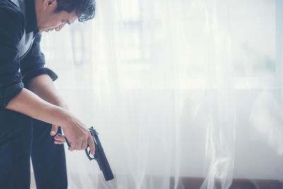 Side view of woman standing against window