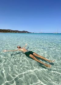 Man swimming in sea against clear blue sky